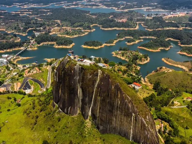 Aerial view of El Peñol Rock, with buildings on its summit, surrounded by the Guatapé reservoir and its green islands