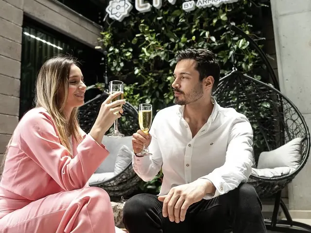 Couple toasting with champagne glasses in front of the vertical garden and the Living by Armóniko sign