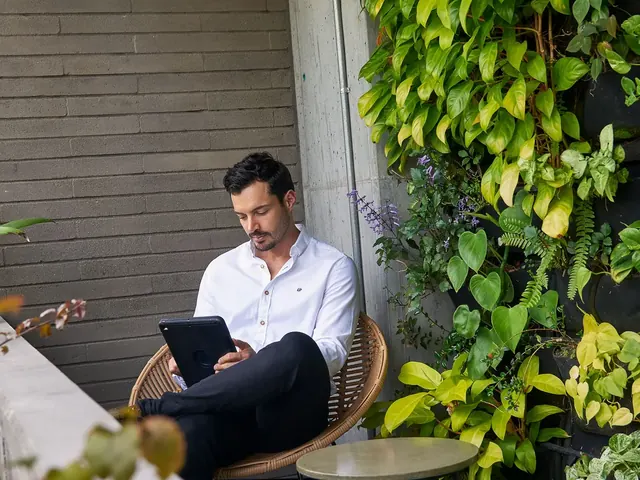 Guest working on a tablet in a wicker chair next to a vertical garden at Living by Armóniko