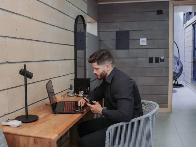 Guest in a black shirt working on a laptop at a wooden desk inside a suite at Living by Armóniko in Laureles, Medellín