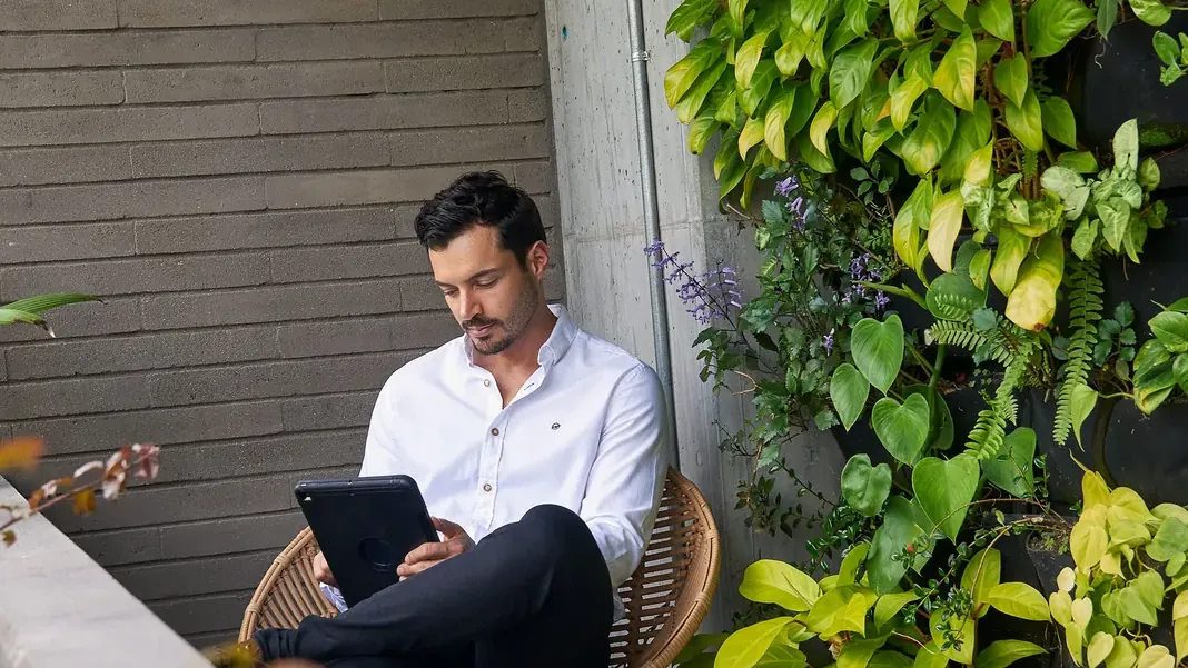 Guest working on a tablet in a wicker chair next to a vertical garden at Living by Armóniko