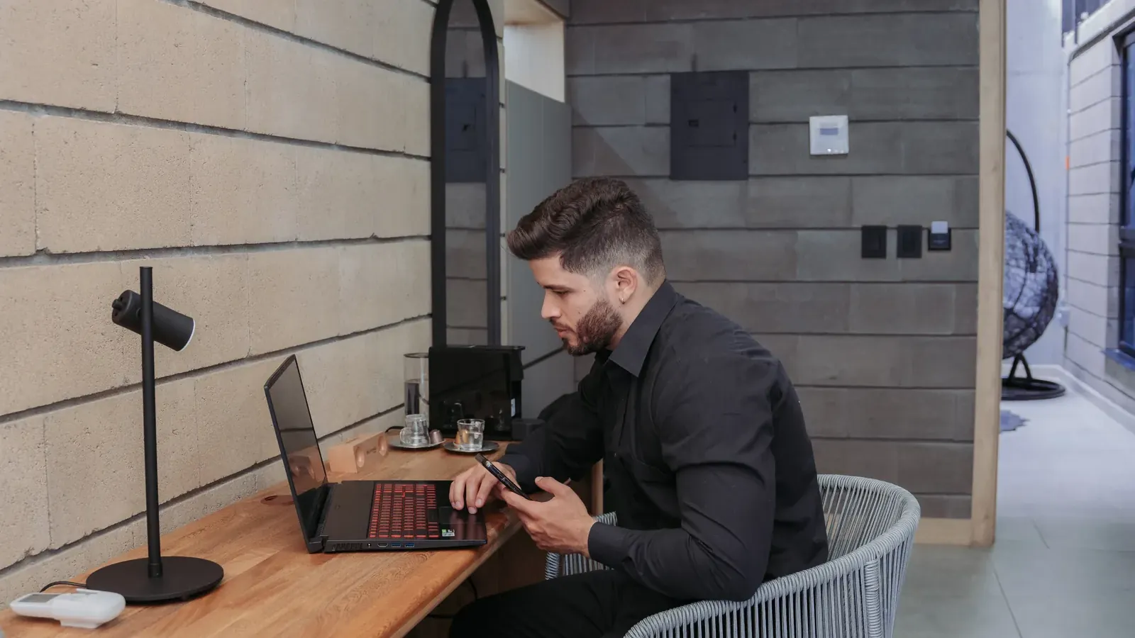 Guest in a black shirt working on a laptop at a wooden desk inside a suite at Living by Armóniko in Laureles, Medellín
