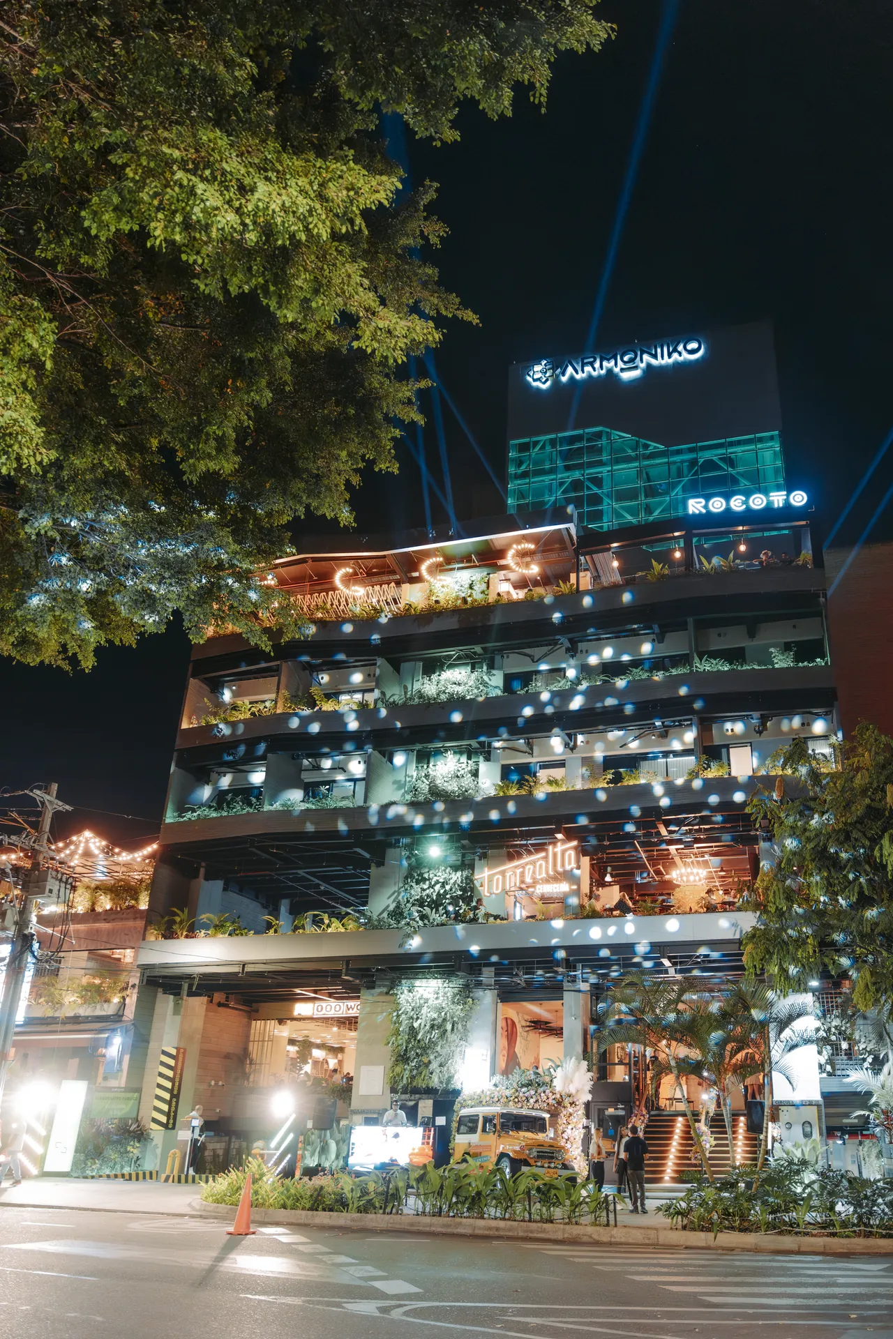 Illuminated façade of Living by Armóniko at night at Circular 75 #38-35, across from Segundo Parque de Laureles, Medellín