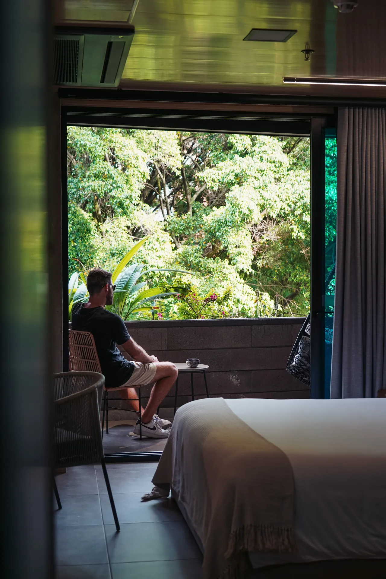 Guest relaxing on the balcony of a suite at Living by Armóniko, surrounded by greenery in Laureles, Medellín