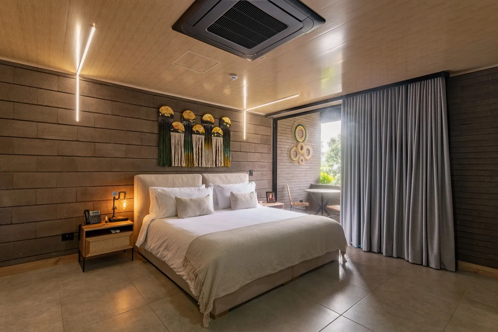 King bed in the Deluxe Suite with macramé art and warm lighting at Living by Armóniko